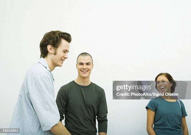 three young adults, laughing, white background - three people white background stock pictures, royalty-free photos & images