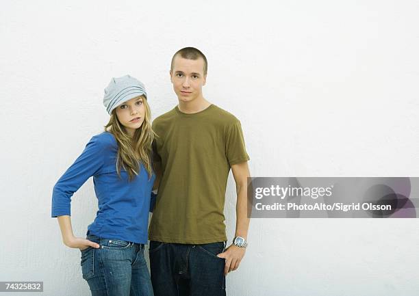 young couple standing with hands in pockets, portrait, white background - skinhead girls - fotografias e filmes do acervo