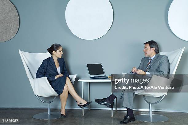 businessman and businesswoman sitting face to face, having discussion - gray shoe fotografías e imágenes de stock