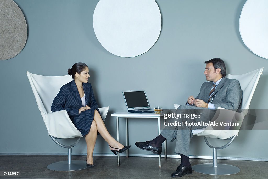 Businessman and businesswoman sitting face to face, having discussion