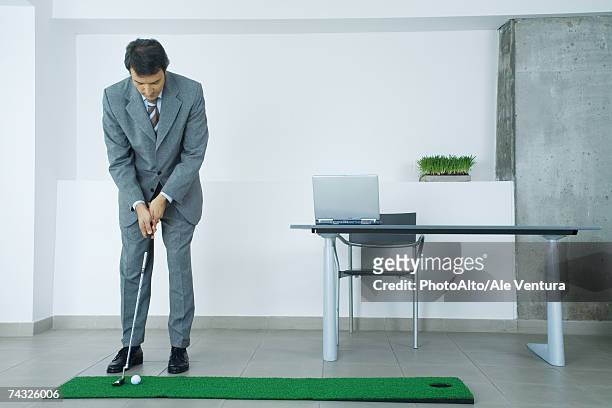 businessman putting on artificial turf in office - putting indoors stock pictures, royalty-free photos & images