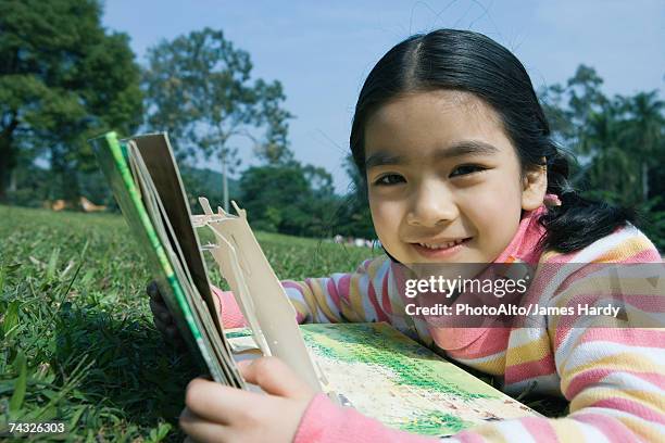 girl lying in grass with pop-up book - pop up book stock-fotos und bilder