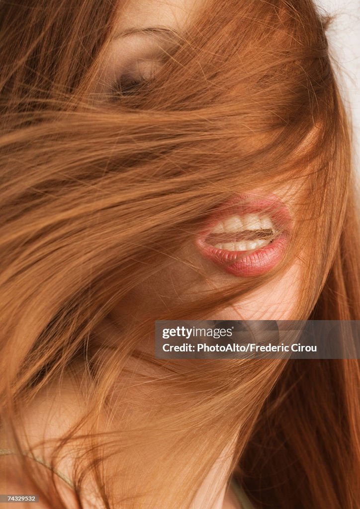 Woman with red hair covering face, mouth open, portrait