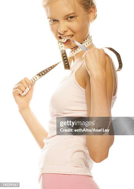 young woman standing with measuring tape around neck and between teeth - women being strangled stock pictures, royalty-free photos & images