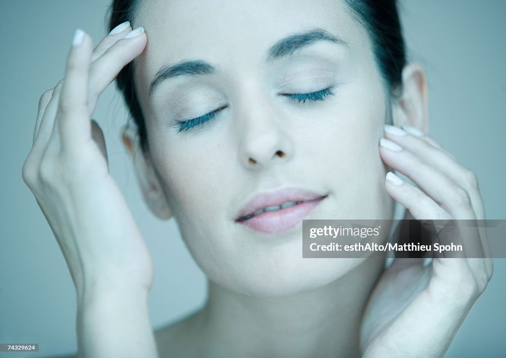 Woman touching face, eyes closed, portrait