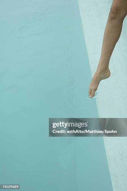 woman's bare leg, touching surface of water with toe - womans bare feet fotografías e imágenes de stock
