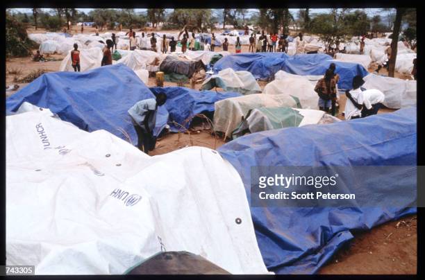 Sudanese refugees and "Lost Boys" stand around covered supplies on June 18, 1992 at a camp inside Kenya. Some 17,000 boys were lured away from home...
