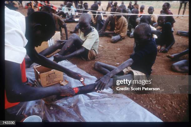 Man remedies the leg of a Sudanese "Lost Boy" on June 18, 1992 at a refugee camp inside Kenya. Some 17,000 boys were lured away from home to receive...