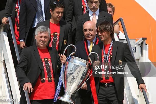 Milan coach Carlo Ancelotti holds the Champion's League trophy with Paolo Maldini followed by Vice-President Adriano Galliani during their arrival at...