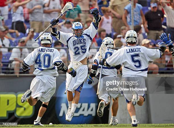 Duke University's Matt Danowski, midfielder Terrence Molinari and midfielder Peter Lamade charge teammate Zack Greer after he scored the winning goal...