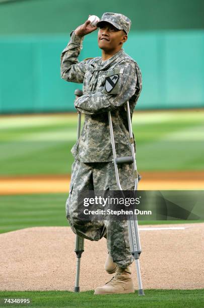 Army Specialist Joseph Bacani throws out the first pitch while on crutches before the game between the Seattle Mariners and the Los Angeles Angels of...