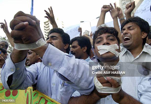 Pakistani journalists gag their mouths and hands with tape as they shout slogans during demonstration against threats received by three journalists,...