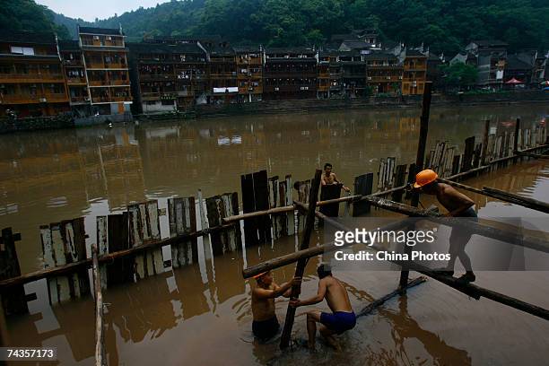 Workers set up scaffolding near a bridge on the Tuojiang River at ancient Fenghuang Town May 29, 2007 in Jishou City of Hunan Province, China....