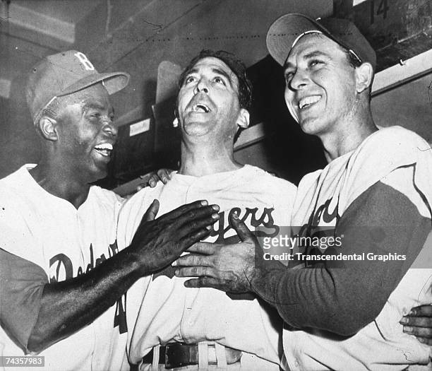 Brooklyn Dodgers Jackie Robinson and Gil Hodges laugh with pitcher Sal Maglie after they nearly gave him a heart attack when scoring the winning run...
