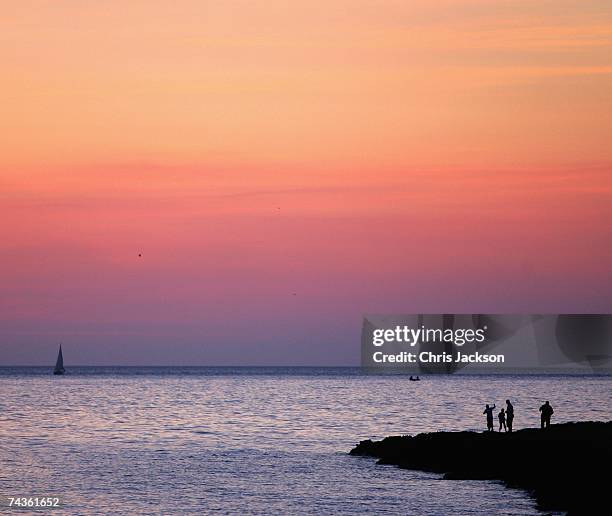 People watch the sun set from rocks outside San Antonio on May 30, 2007 in Ibiza, Spain. Ibiza remains one of the world's top holiday destinations...