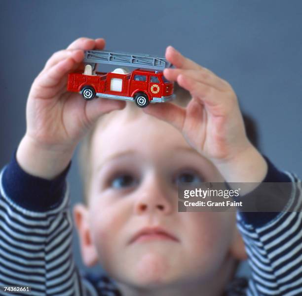 boy (2-4) holding up toy fire-engine truck (focus on truck) - toy truck stock pictures, royalty-free photos & images