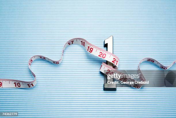 metal number '1' wrapped with measure tape, elevated view - laser tape measure stock pictures, royalty-free photos & images