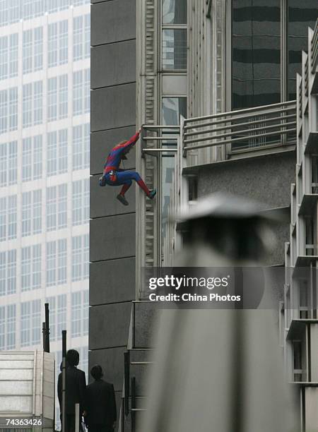 French urban climber Alain Robert, dressed as the fictional cartoon character 'Spider-Man' waves to spectators as he climbs down the facade of the...