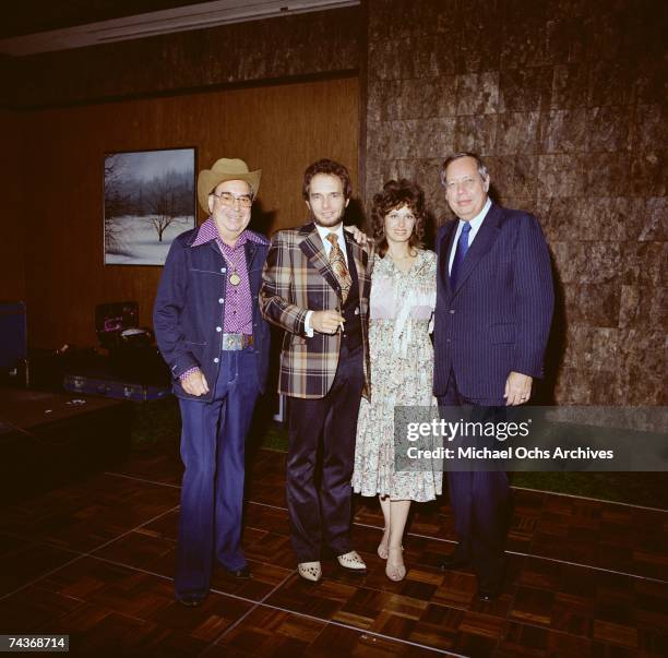 Country singer Merle Haggard poses for a mid 1970's portrait with some unidentified people.