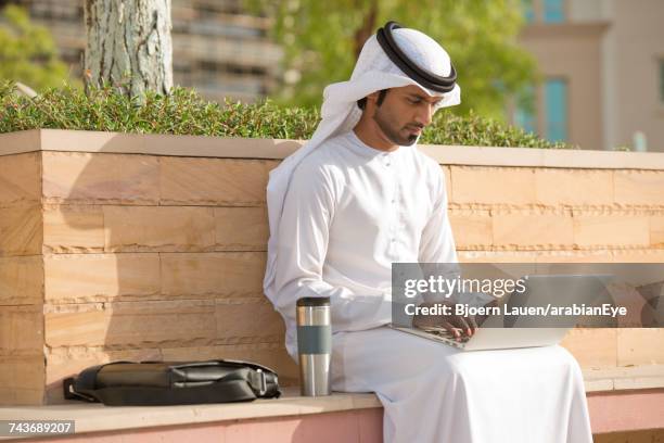 emirati businessman working on laptop.,emirati businessman working on laptop. - emirati laptop stock pictures, royalty-free photos & images