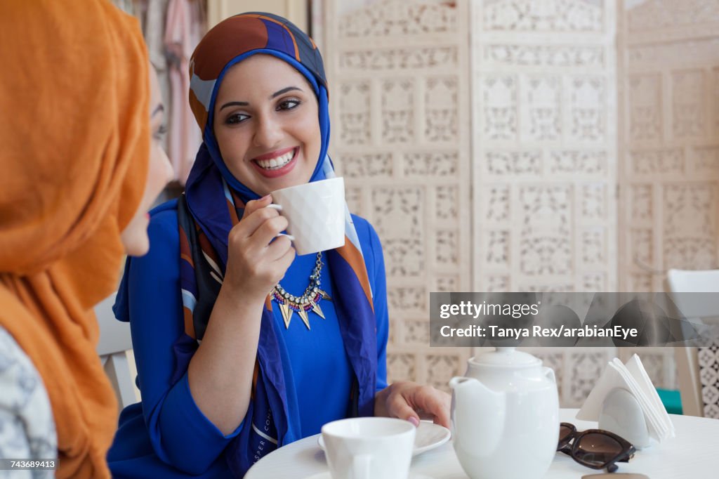 Arab women chatting at café. 