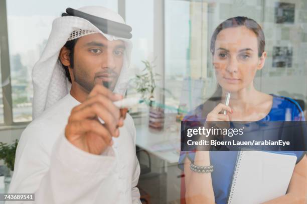 emirati businessman discussing project with colleague at office.,emirati businessman discussing project with colleague at office. - arab businesswoman with books fotografías e imágenes de stock