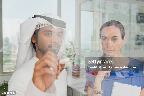 emirati businessman discussing project with colleague at office. - arab businesswoman with books stock-fotos und bilder