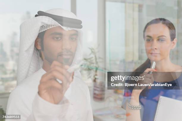 emirati businessman discussing project with colleague at office. - arab businesswoman with books fotografías e imágenes de stock