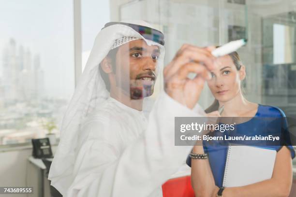 emirati businessman discussing project with colleague at office. - arab businesswoman with books fotografías e imágenes de stock