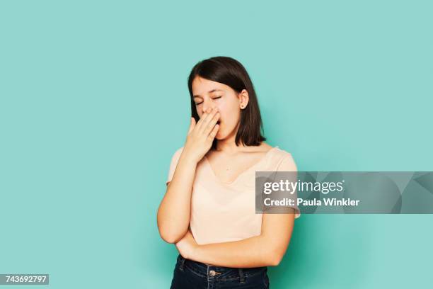 tired girl yawning while standing on turquoise colored - yawning stock pictures, royalty-free photos & images
