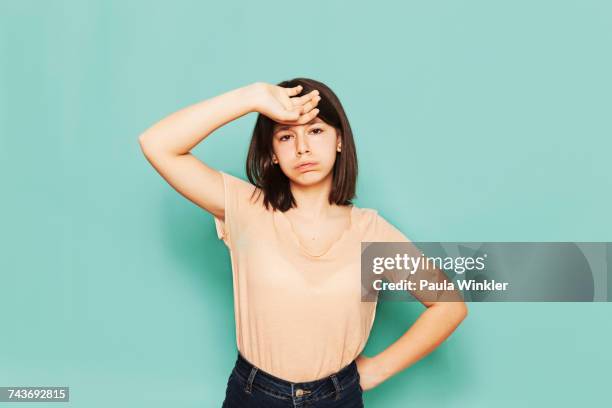 portrait of tired girl standing against turquoise background - ein mädchen allein stock-fotos und bilder