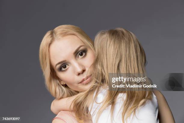 portrait of mother carrying blond daughter against gray background - woman lipstick rearview stock pictures, royalty-free photos & images