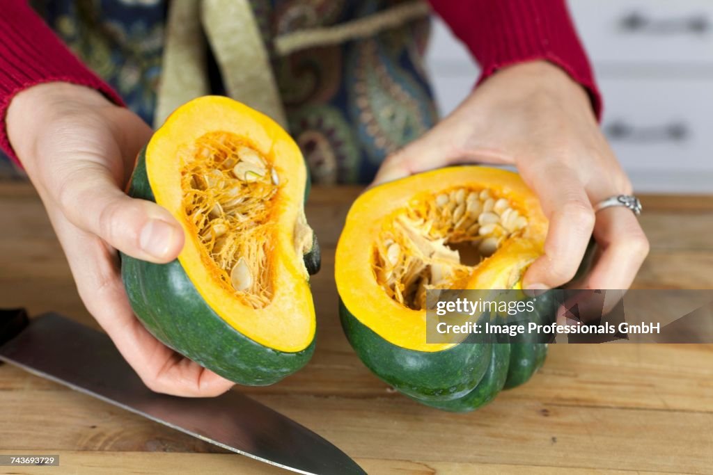 A woman holding two halves of acorn squash