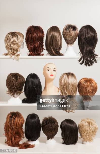 mannequin head amidst various wigs on shelves against white background - mannequin blonde stockfoto's en -beelden