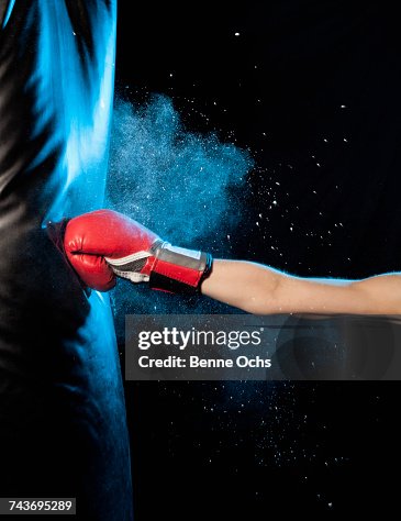 Cropped image of man hitting punching bag against black background Cropped image of man hitting punching bag against black background