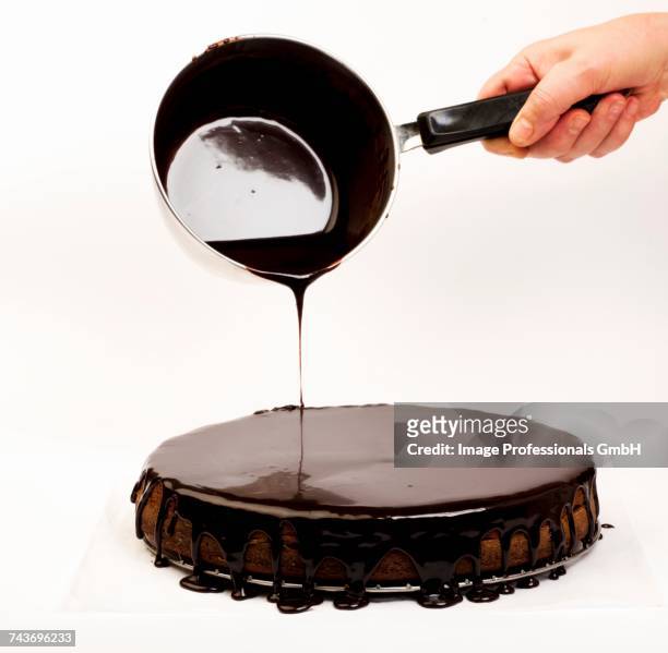 chocolate glaze being poured over a sachertorte - sachertorte stock pictures, royalty-free photos & images