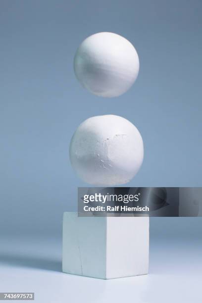 White spheres levitating over block shape against gray background