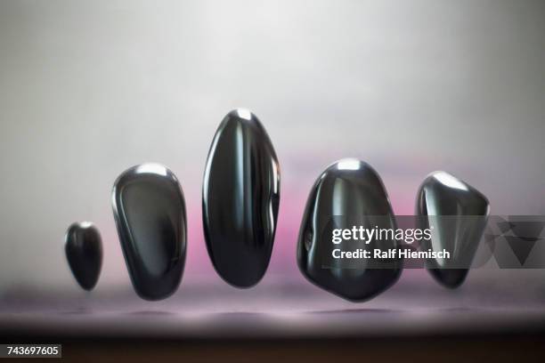 various shape of shiny pebbles levitating against gray background - rock object stock pictures, royalty-free photos & images
