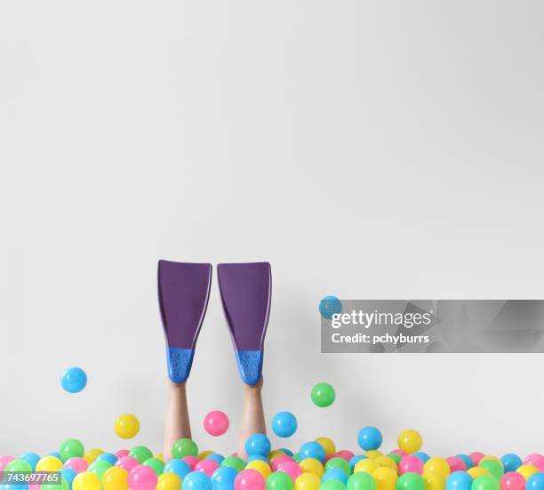 woman wearing scuba fins diving into a conceptual ocean of plastic balls - ダイビング用のフィン ストックフォトと画像