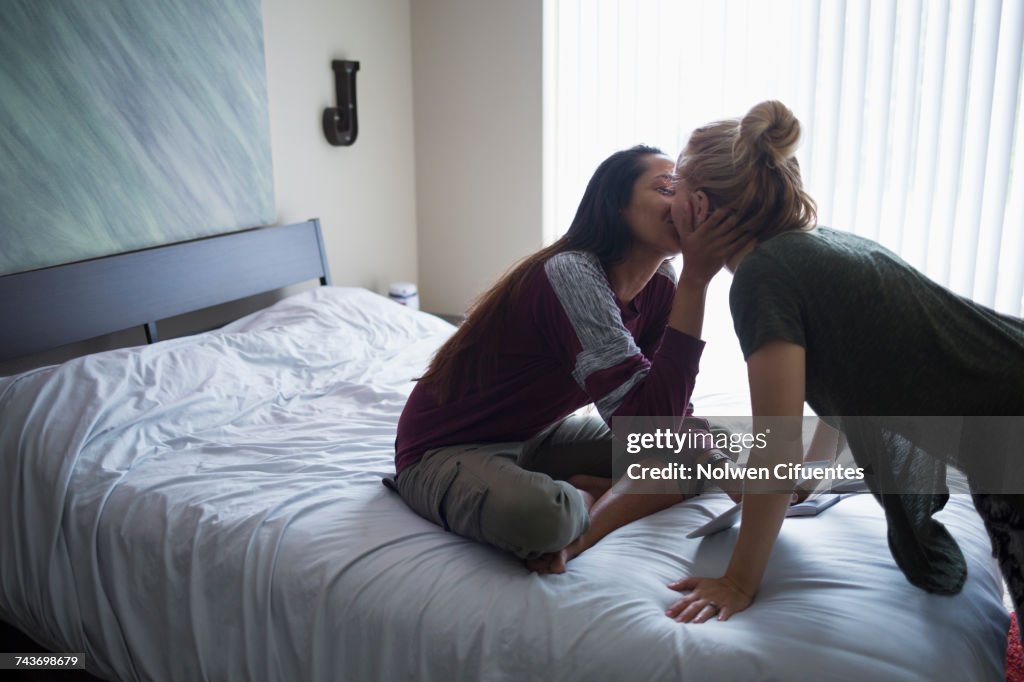 Young lesbian couple kissing on bed at home