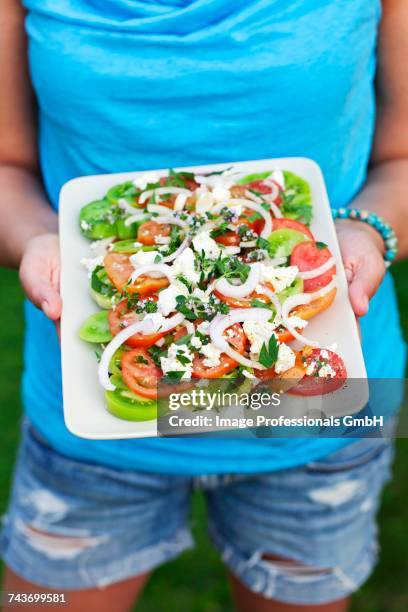 a woman holding a plate of greek salad - fetta - fotografias e filmes do acervo