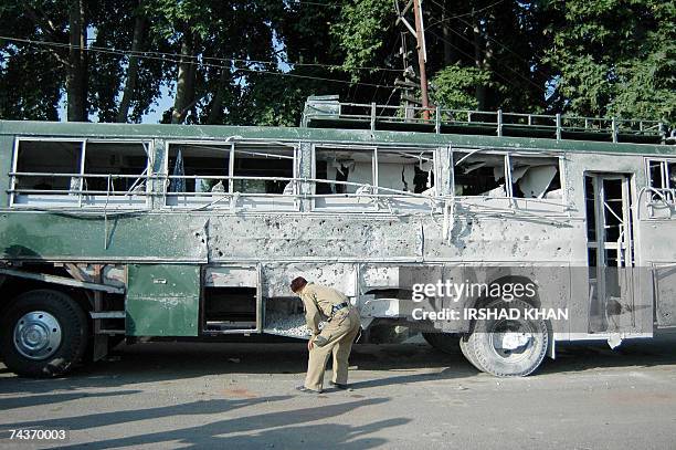 An Indian paramilitary soldier looks at the damaged Indian Army bus after a blast in Srinagar, 01 June 2007. An explosion in the Rajbagh area of...