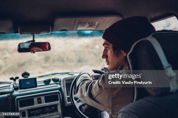 rear view of man driving sports utility vehicle - winter hat stock pictures, royalty-free photos & images