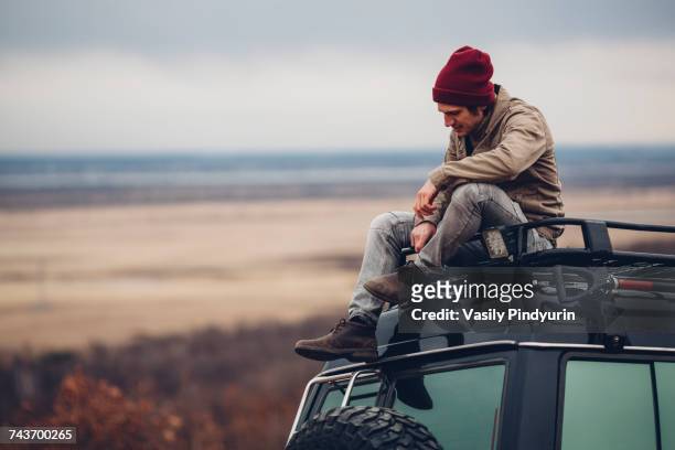 man sitting on top of sports utility vehicle against landscape, blagoveschensk, amur, russia - sitting on top of car stock pictures, royalty-free photos & images
