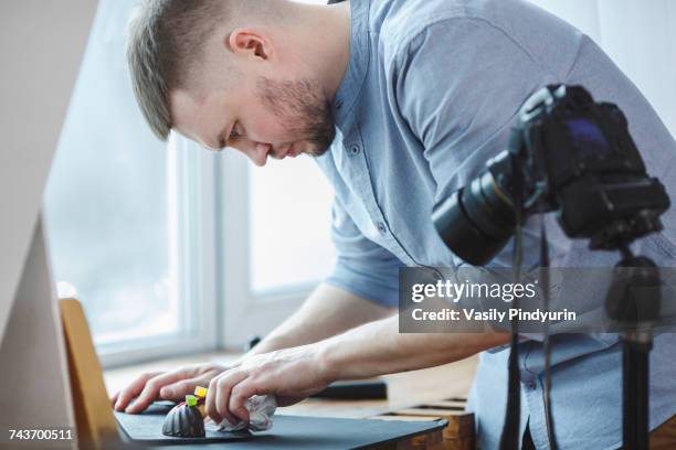 man cleaning food plate while standing by tripod camera at studio - atelier food stock-fotos und bilder