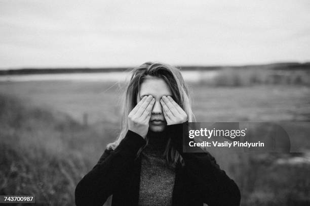 teenage girl covering eyes while standing on field against sky - hands covering eyes stock pictures, royalty-free photos & images