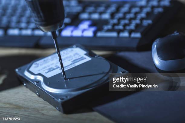 close-up of drill on hard drive by computer keyboard at table - data destruction stock pictures, royalty-free photos & images