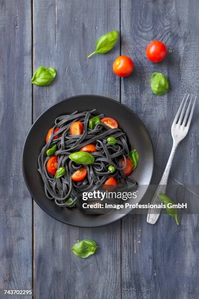 black squid ink pasta with tomatoes and basil - squid ink pasta stock pictures, royalty-free photos & images