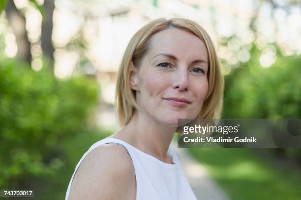 close-up portrait of confident smiling mature woman with short blond hair at park - short trees bildbanksfoton och bilder