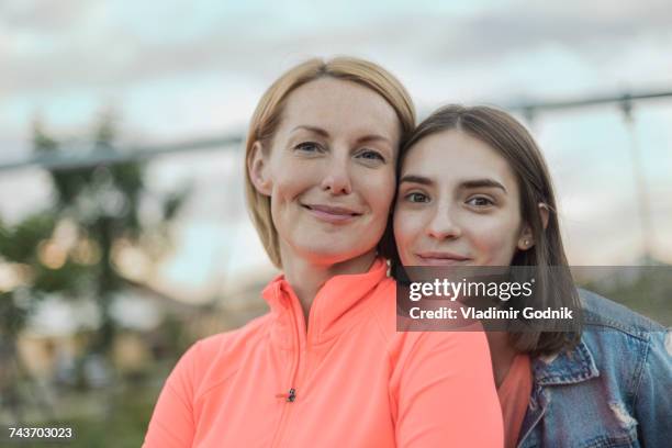 portrait of smiling mother and daughter against sky at park - generationsunterschied stock-fotos und bilder